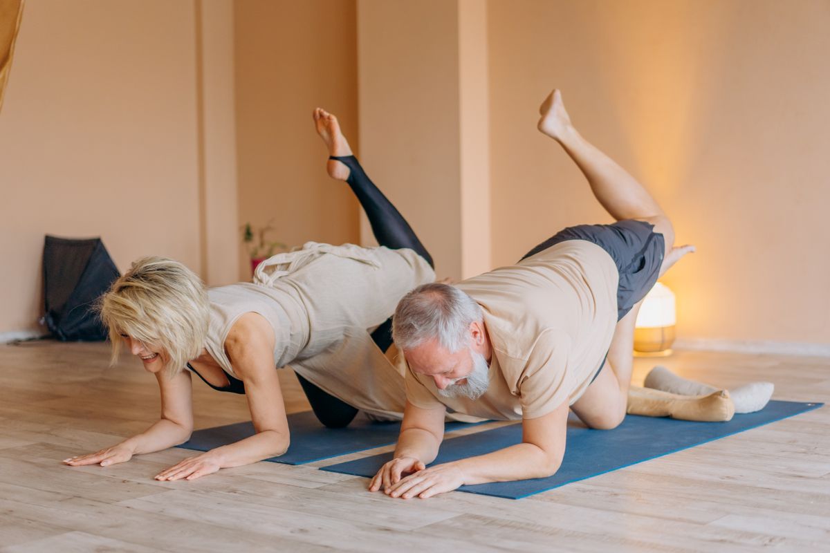 A small group of older adults practicing supported balance exercises with an instructor in a bright, welcoming studio.