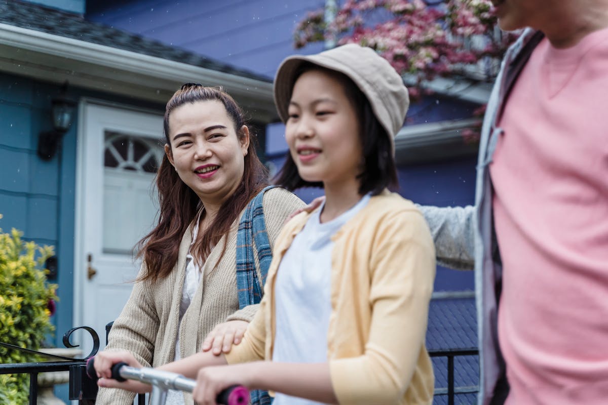 An adult child walking outdoors with their older parent, both smiling and relaxed.